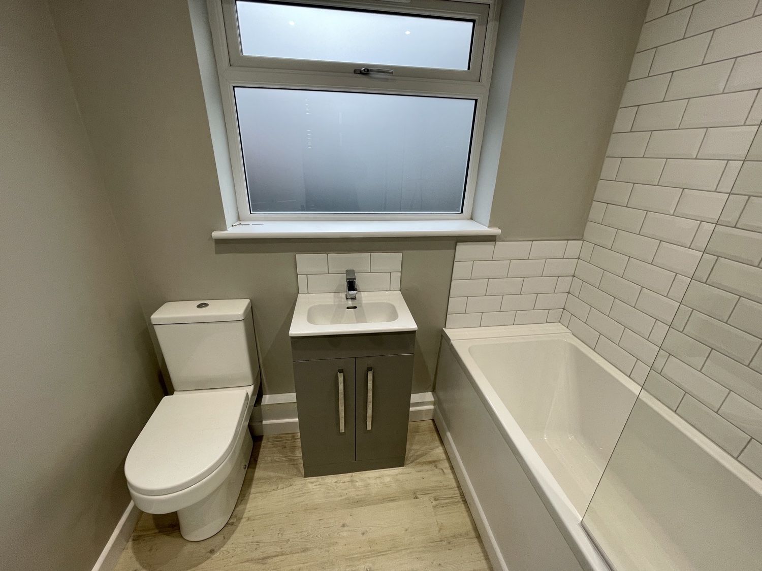 Bathroom after a complete refit: toilet, vanity basin under the window and bath