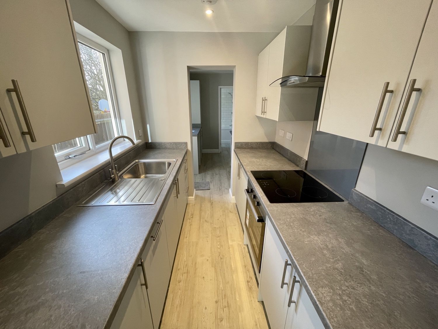 Kitchen after a complete refit: white units, grey worktops, built-in oven and hob