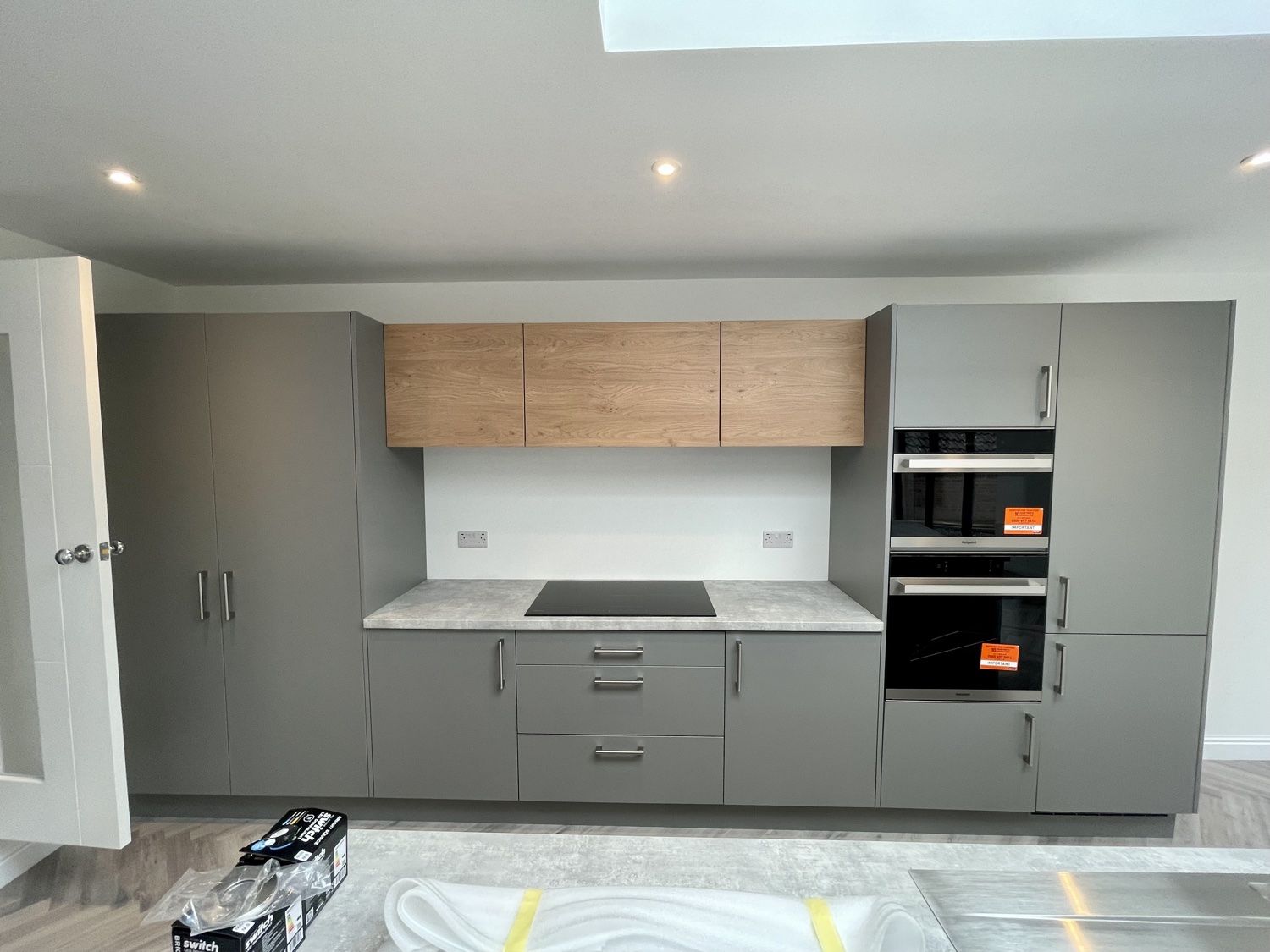 New kitchen with grey units, oak-effect wall units, built-in ovens and hob