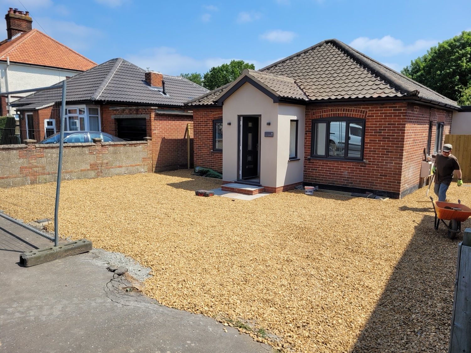 Bungalow after a complete refurbishment: new rendered porch, dark grey windows and door, gravel frontage